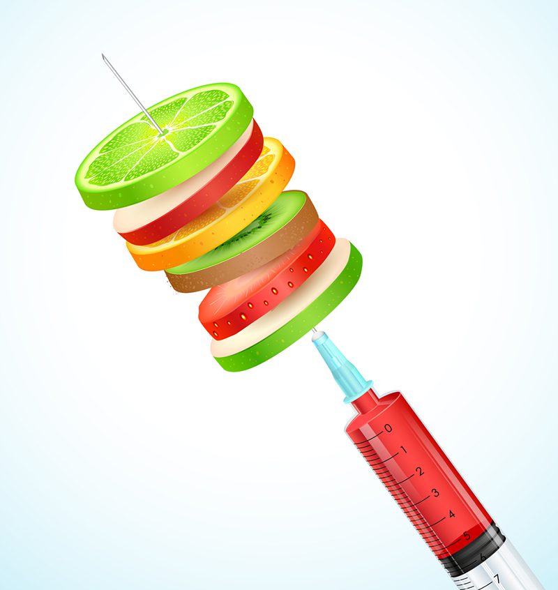 A red syringe with a green apple, orange and lime slice.