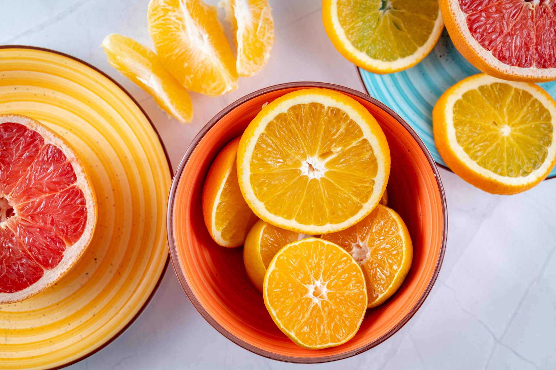 Fresh oranges and grapefruit arranged on colorful plates